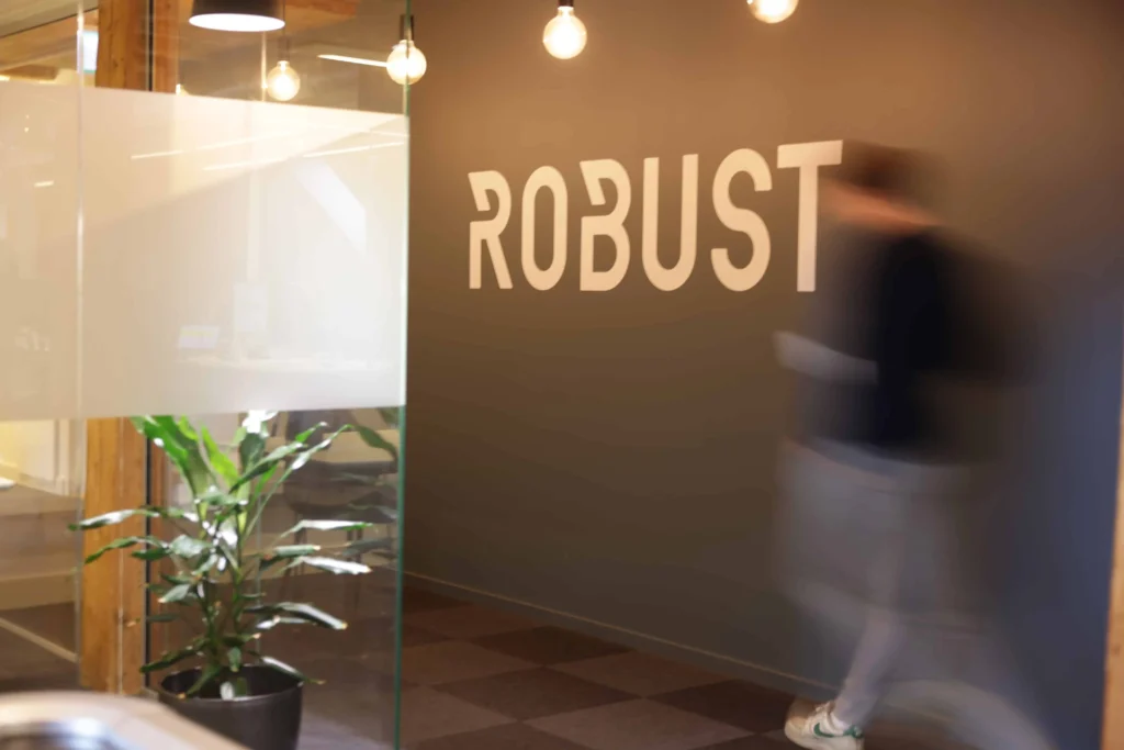 Robust logo på kontorlokale med moderne design og grønt planteinnslag.