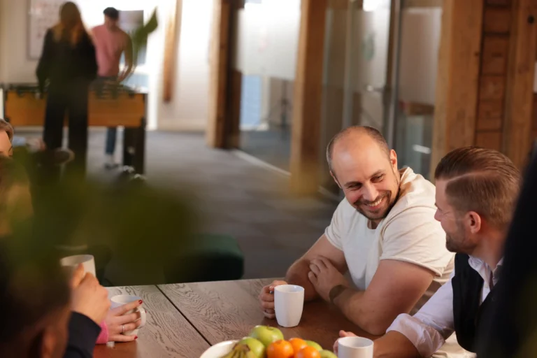 Mennesker som har en uformell samtale rundt et bord i et moderne kontormiljø.