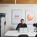 Et bilde av en person som jobber foran en laptop i et moderne kontor med profesjonelt videoutstyr.