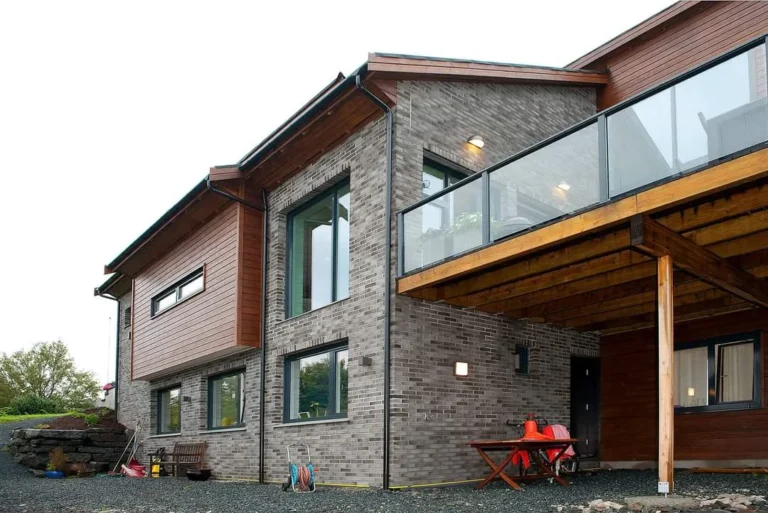 Moderne bolig med kombinasjon av murstein og tre, stor balkong og store vinduer.