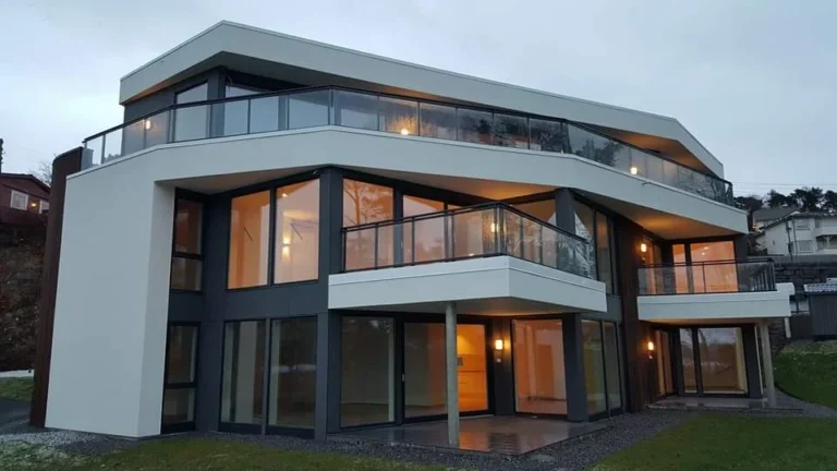 Modern flermannsbolig med store glassflater og balkonger i naturskjønne omgivelser.