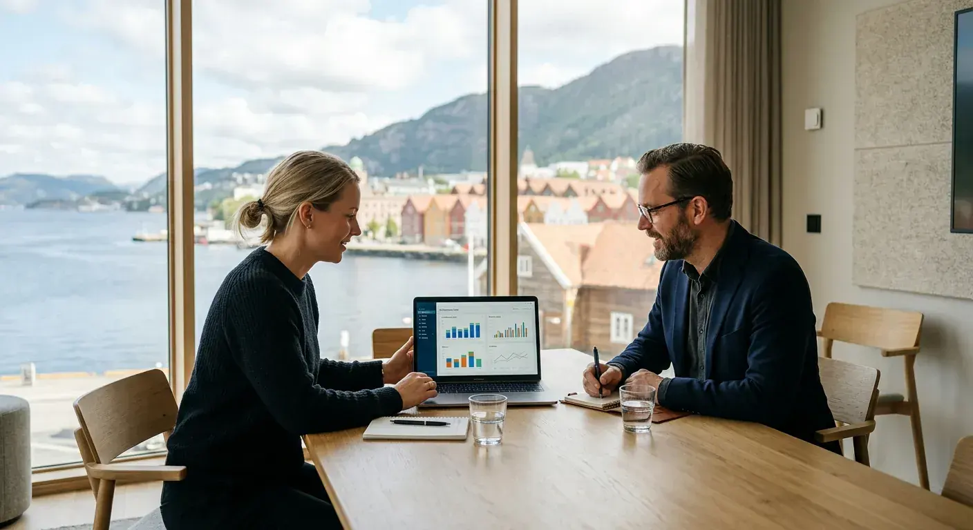 Et moderne, lyst møterom i Bergen der to rådgivere analyserer markedsdata på en bærbar datamaskin
